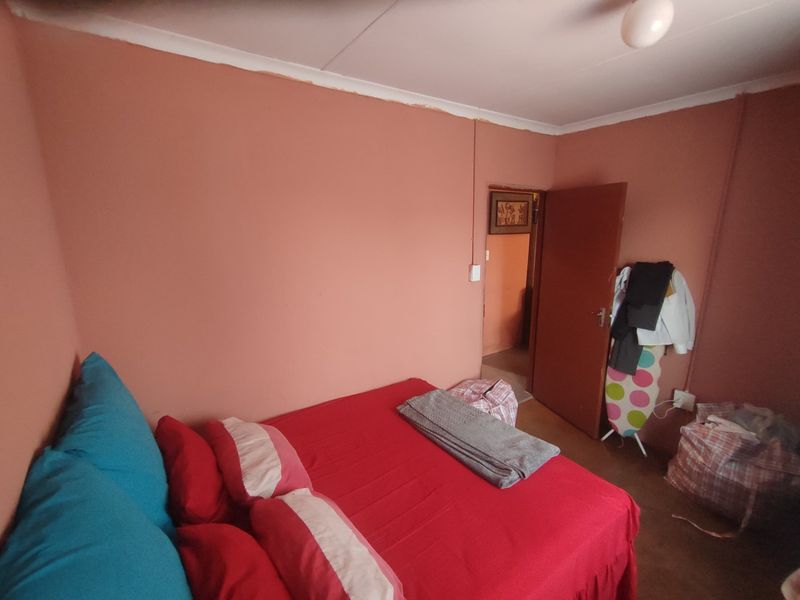 A bedroom featuring painted walls, cove cornicing, and a central ceiling light fixture, offering a blank canvas for potential interior updates.
