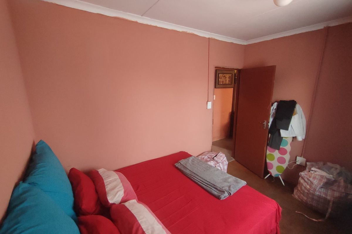 A bedroom featuring painted walls, cove cornicing, and a central ceiling light fixture, offering a blank canvas for potential interior updates.