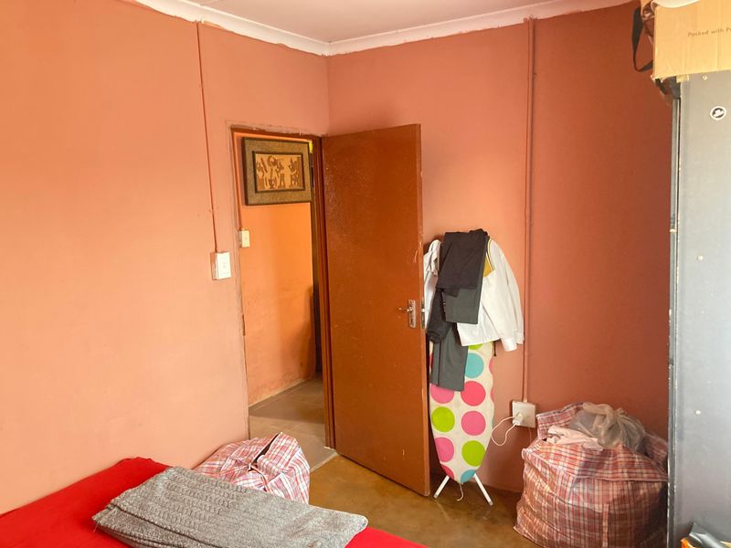 A bedroom featuring painted walls with exposed electrical conduit and a standard internal door, requiring cosmetic updates to improve the overall finish.