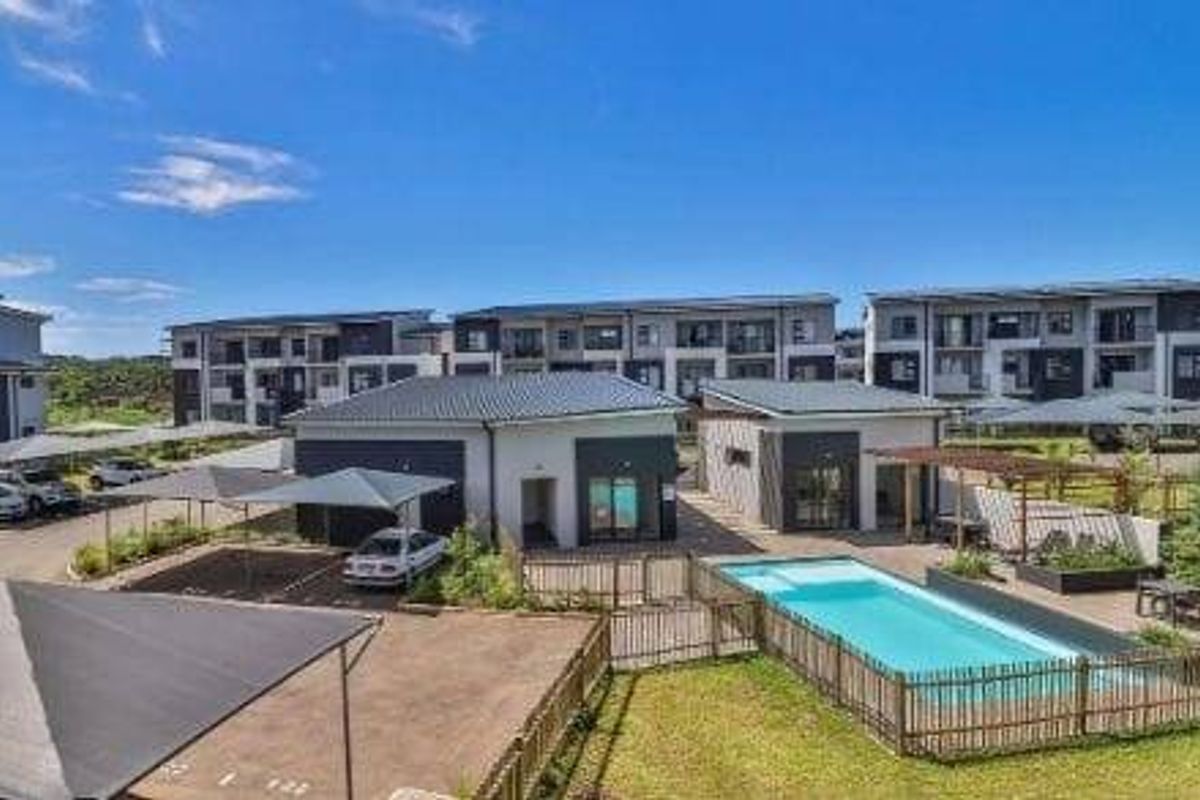 Aerial view of the apartment complex featuring a swimming pool, communal parking carports, and landscaped outdoor areas.