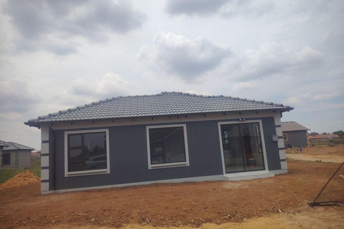A modern single-story house exterior featuring dark grey painted walls, a tiled hip roof, and aluminium-framed windows and sliding glass doors.