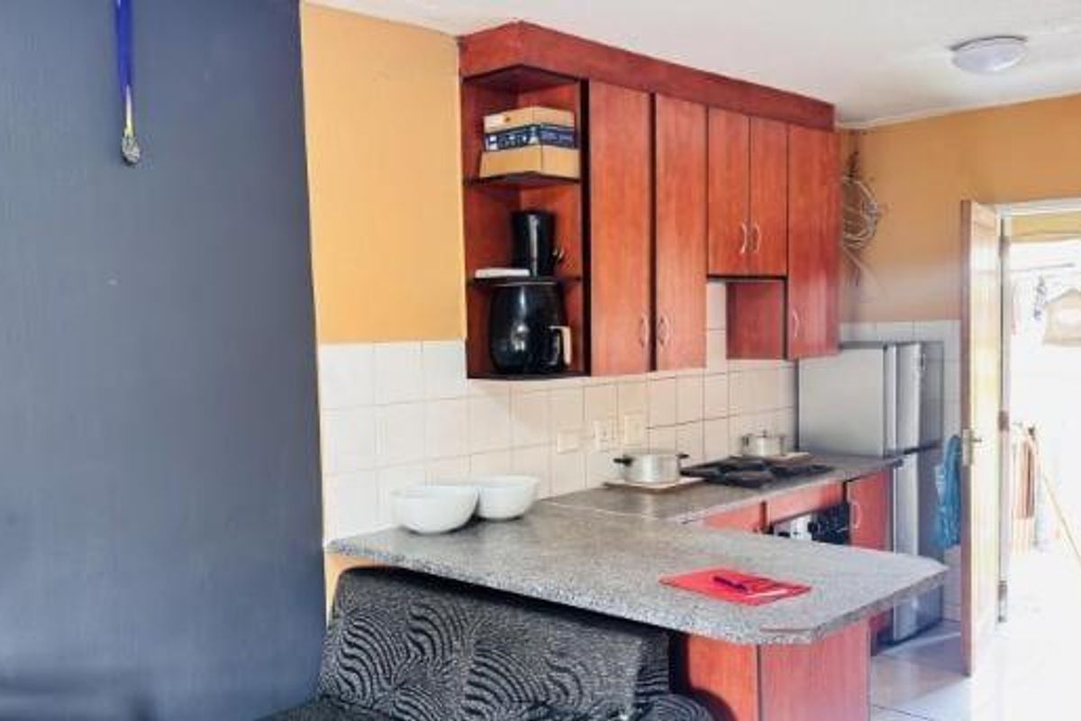 A functional kitchen featuring wooden cabinetry, laminate countertops, a gas hob, and a double bowl sink with direct access to the exterior.