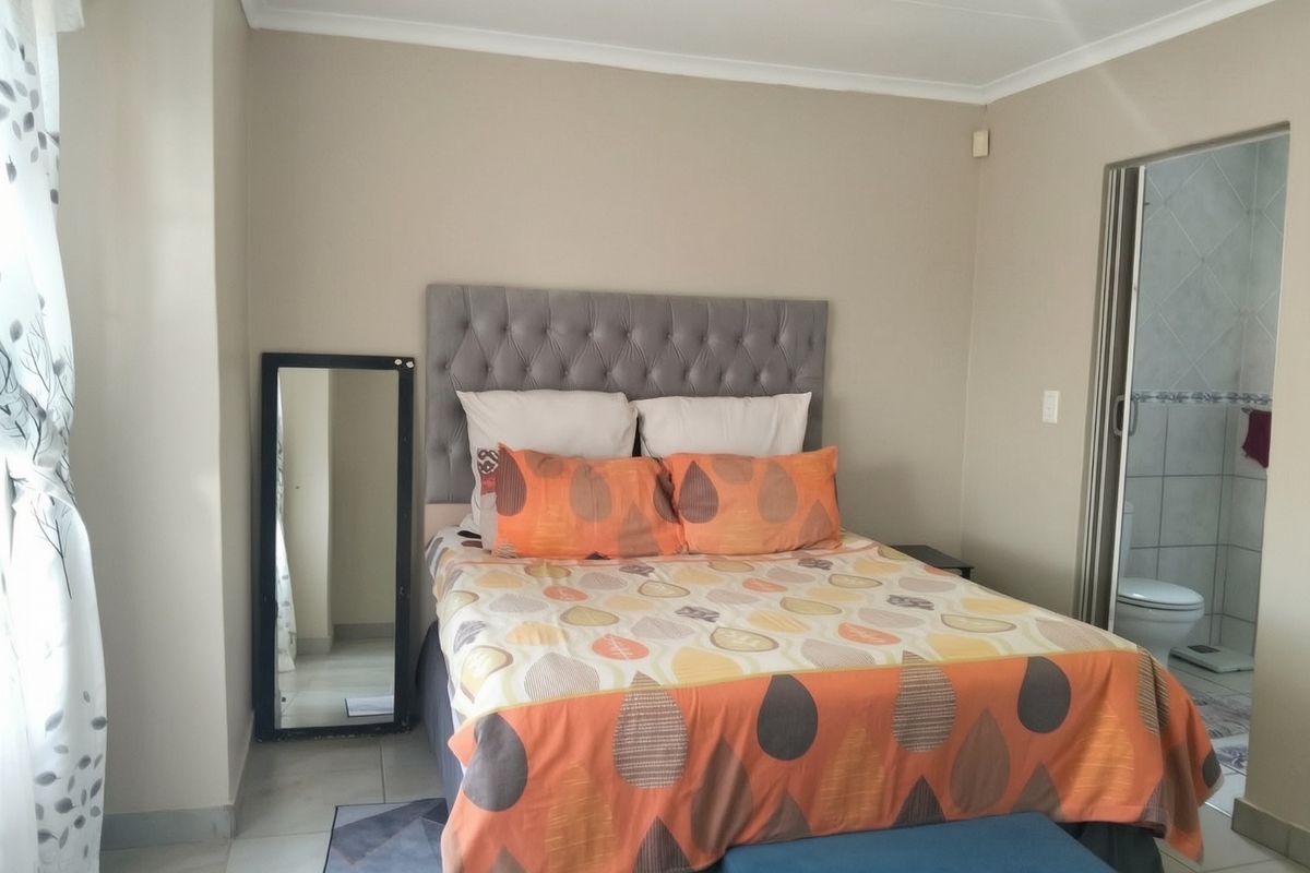 A bedroom featuring tiled flooring and direct access to an en-suite bathroom, providing a functional and well-lit living space.