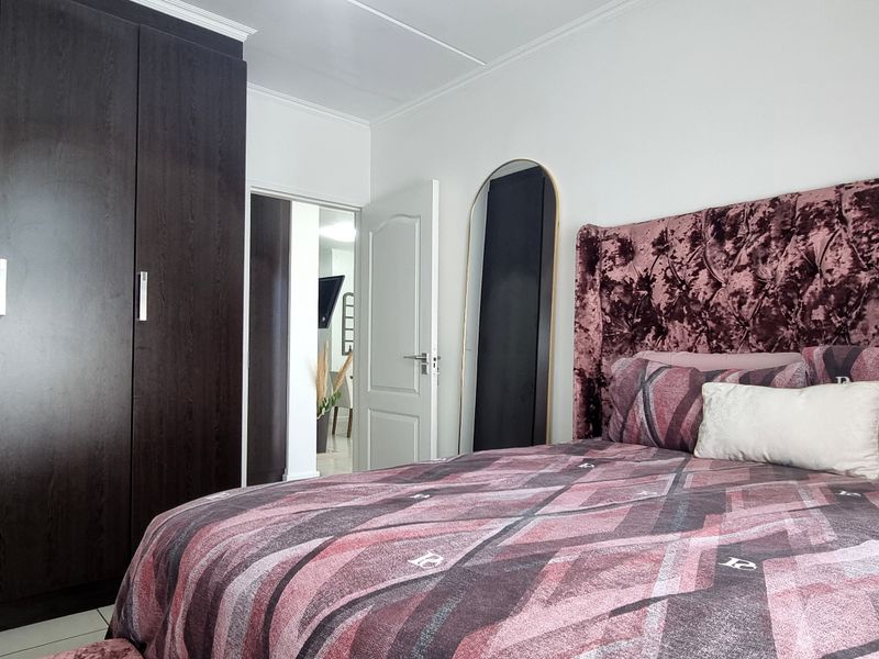 A well-maintained bedroom featuring a large dark wood built-in wardrobe and classic coved ceiling detailing.