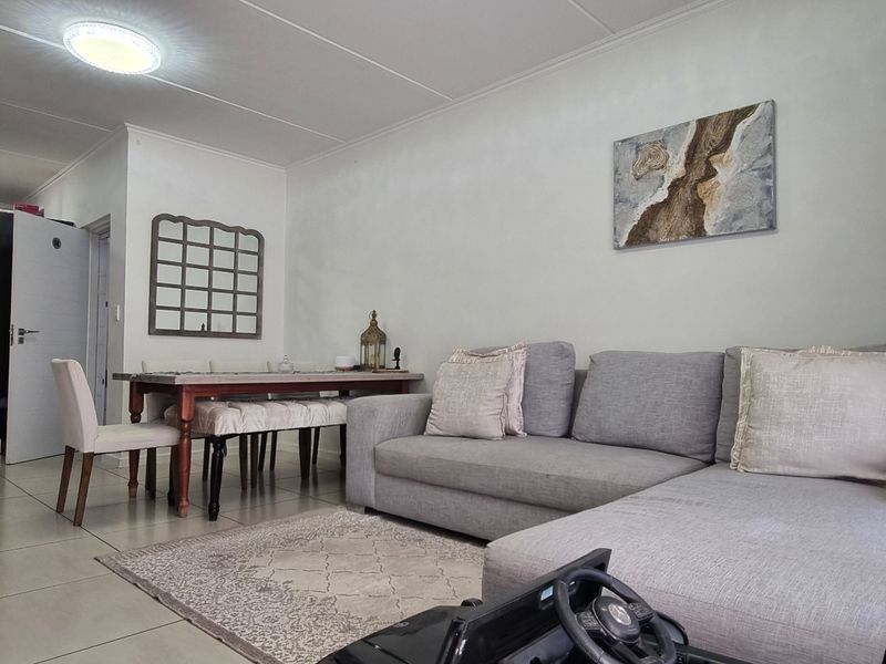 An open-plan living and dining area featuring tiled flooring, neutral walls, and a functional kitchen space with built-in cabinetry.