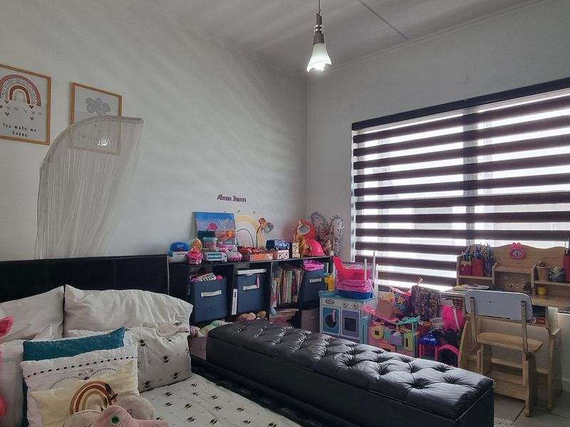 A bedroom featuring tiled flooring, a pendant light fixture, and modern zebra blinds, providing a functional space with natural light control.