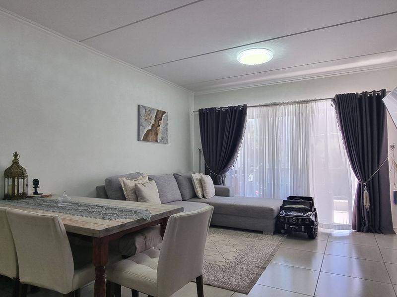 An open-plan living and dining area featuring tiled flooring, a feature wall, and a sliding glass door providing access to the exterior.