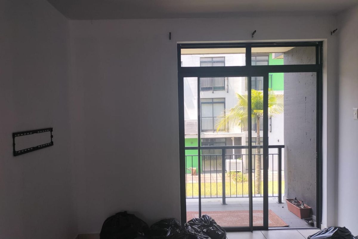 An empty living room featuring tiled flooring and a large sliding glass door providing access to a private balcony.