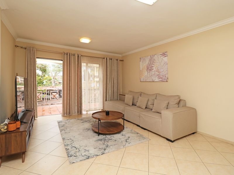 A bright living room featuring tiled flooring and sliding glass doors that provide direct access to an outdoor patio area.