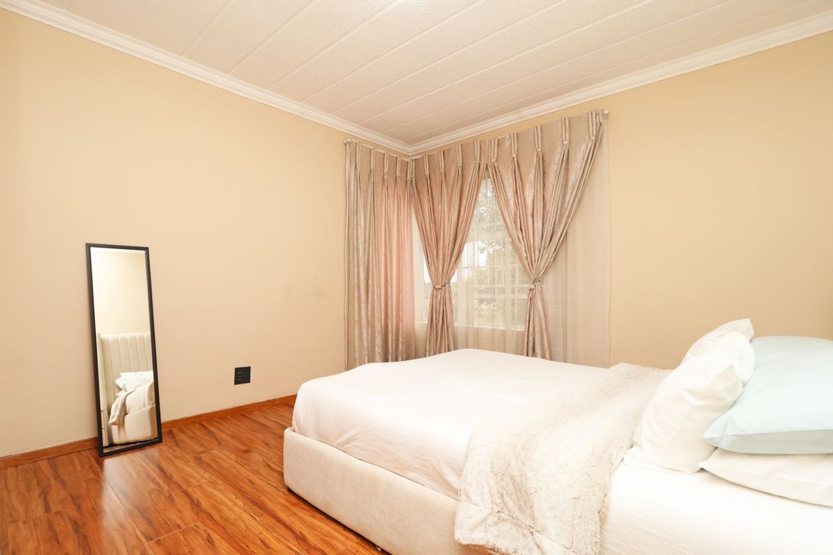 A bedroom featuring laminate flooring, textured ceiling with cornice detailing, and a corner window arrangement.