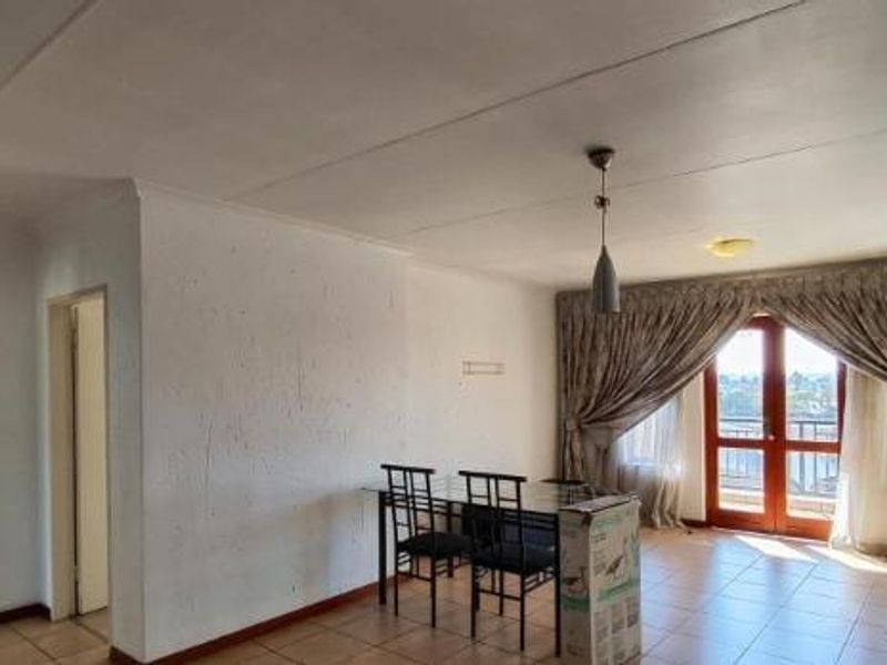 Open plan living and dining area featuring tiled flooring and direct access to a balcony through sliding glass doors.