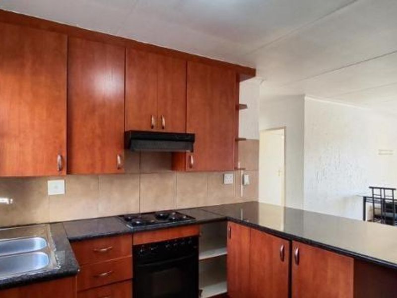 Open plan kitchen featuring laminate cabinetry, granite countertops, built-in oven, and hob, flowing into an adjacent dining area.