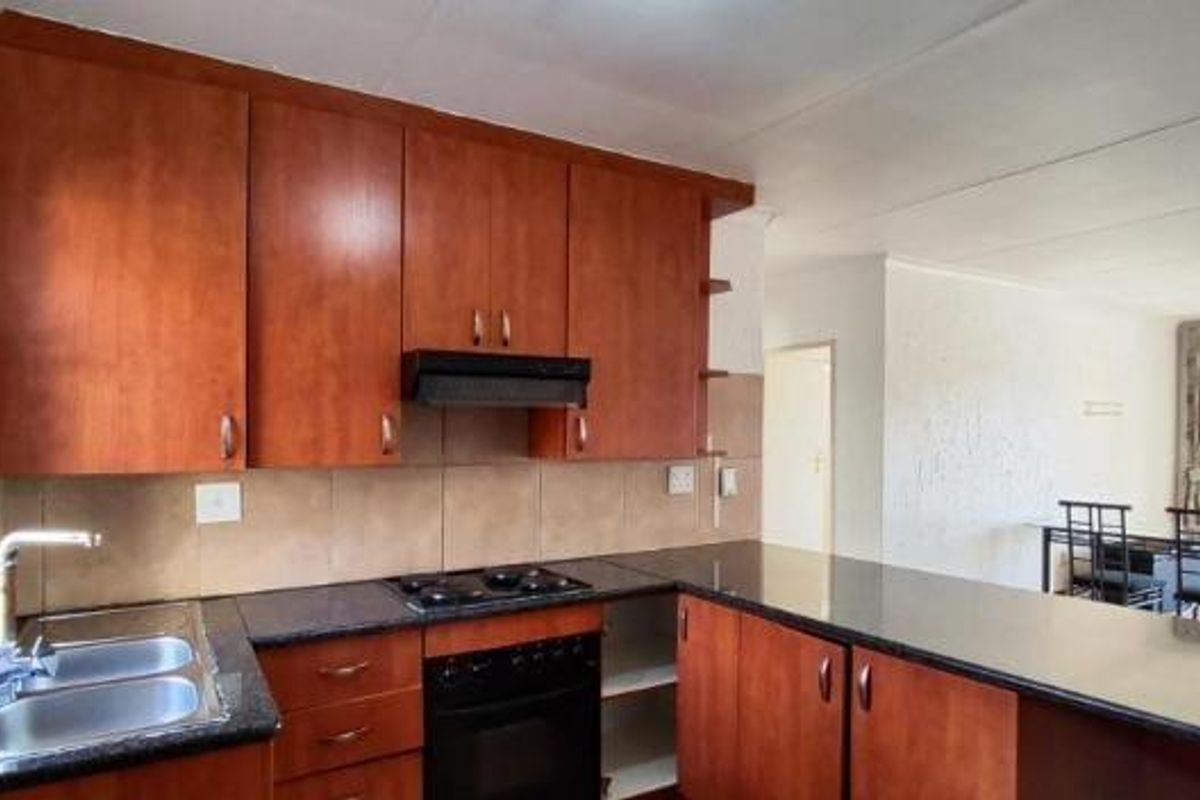 Open plan kitchen featuring laminate cabinetry, granite countertops, built-in oven, and hob, flowing into an adjacent dining area.
