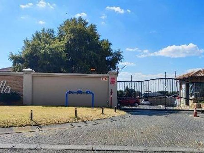 The main entrance to Villa Daniella complex, featuring a secure gated access point, perimeter walling, and a guard house.