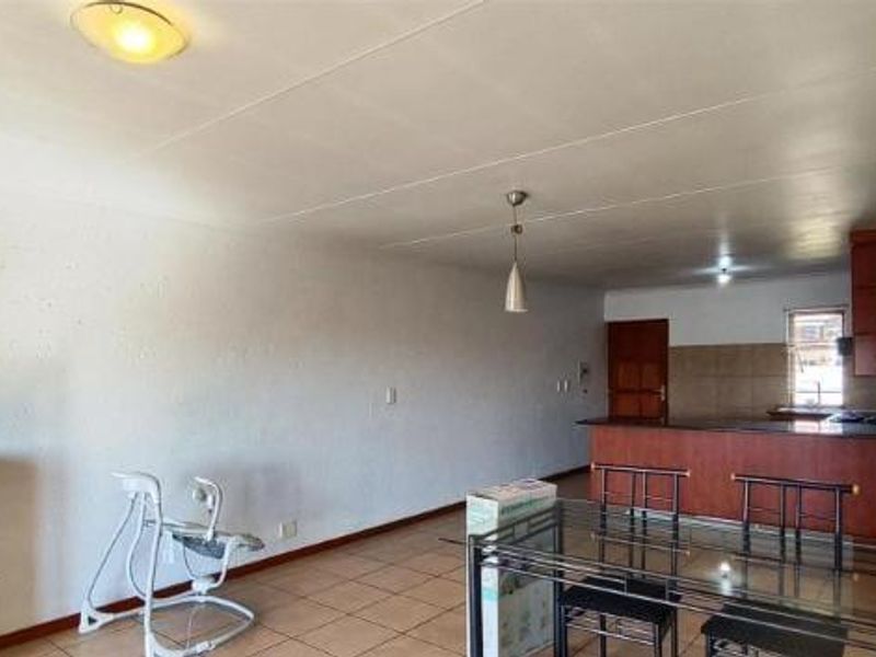 Open-plan living and dining area featuring tiled flooring, a breakfast bar, and integrated kitchen cabinetry.