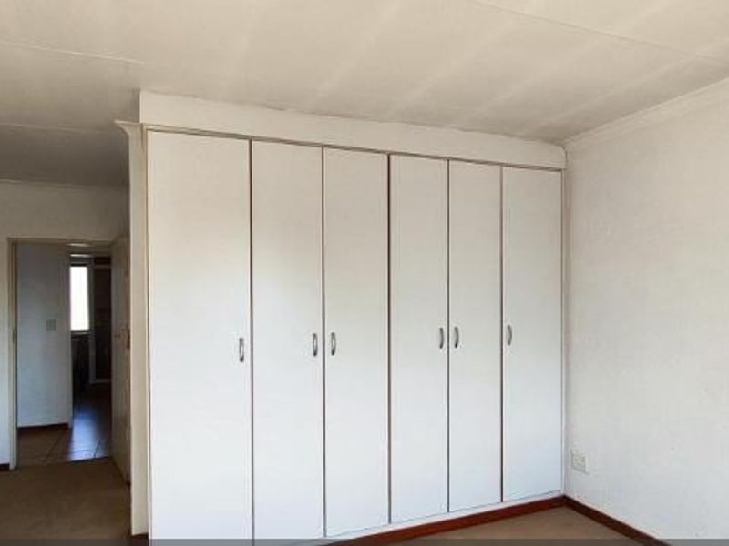 An empty bedroom featuring built-in cupboards, carpeted flooring, and coved ceilings, offering a blank canvas for personalization.