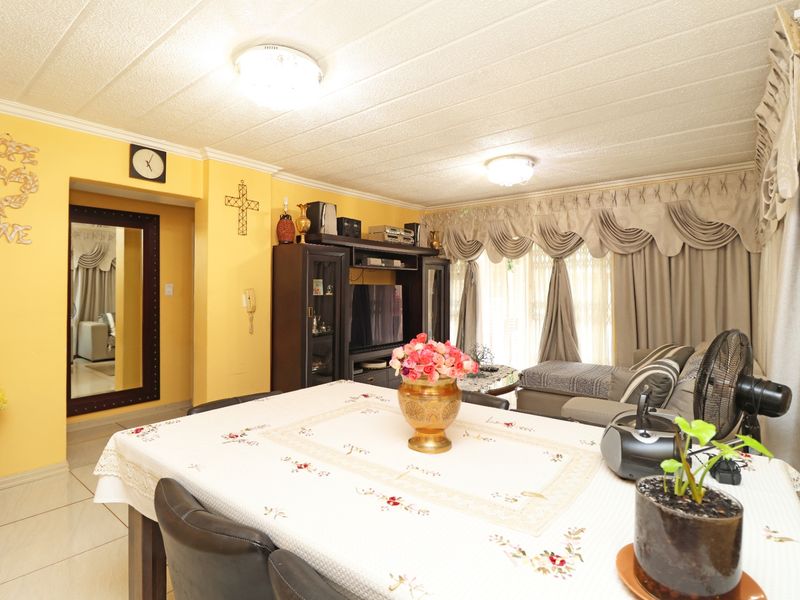 Open plan living and dining area featuring tiled flooring, textured ceilings with coving, and a built-in wall mirror.