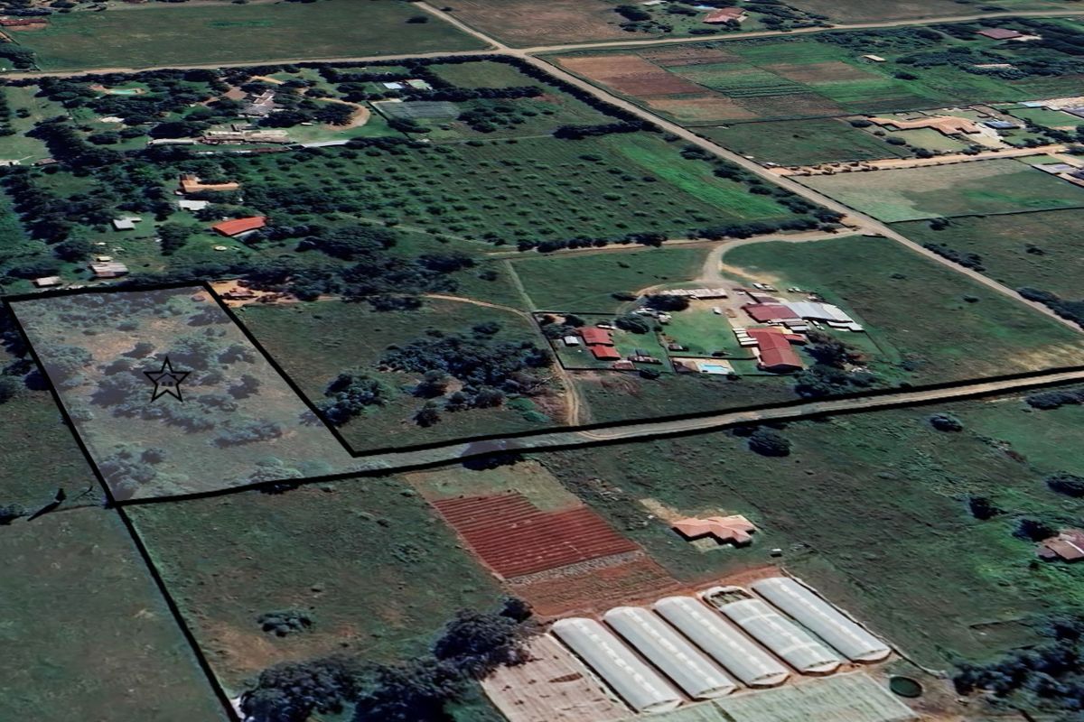 An aerial view of a vacant residential plot of land, showing the surrounding rural landscape and property boundaries.
