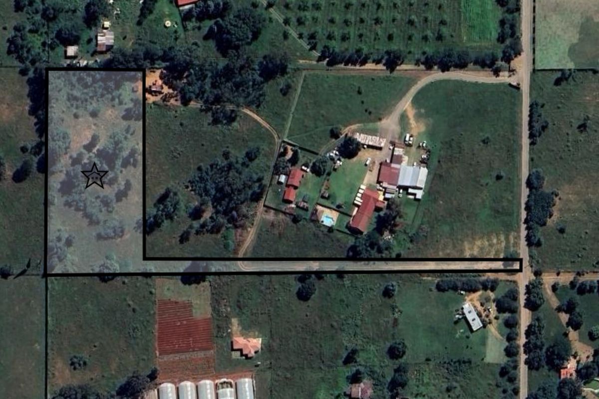 Aerial view of a vacant residential land plot with established vegetation and boundary markings.