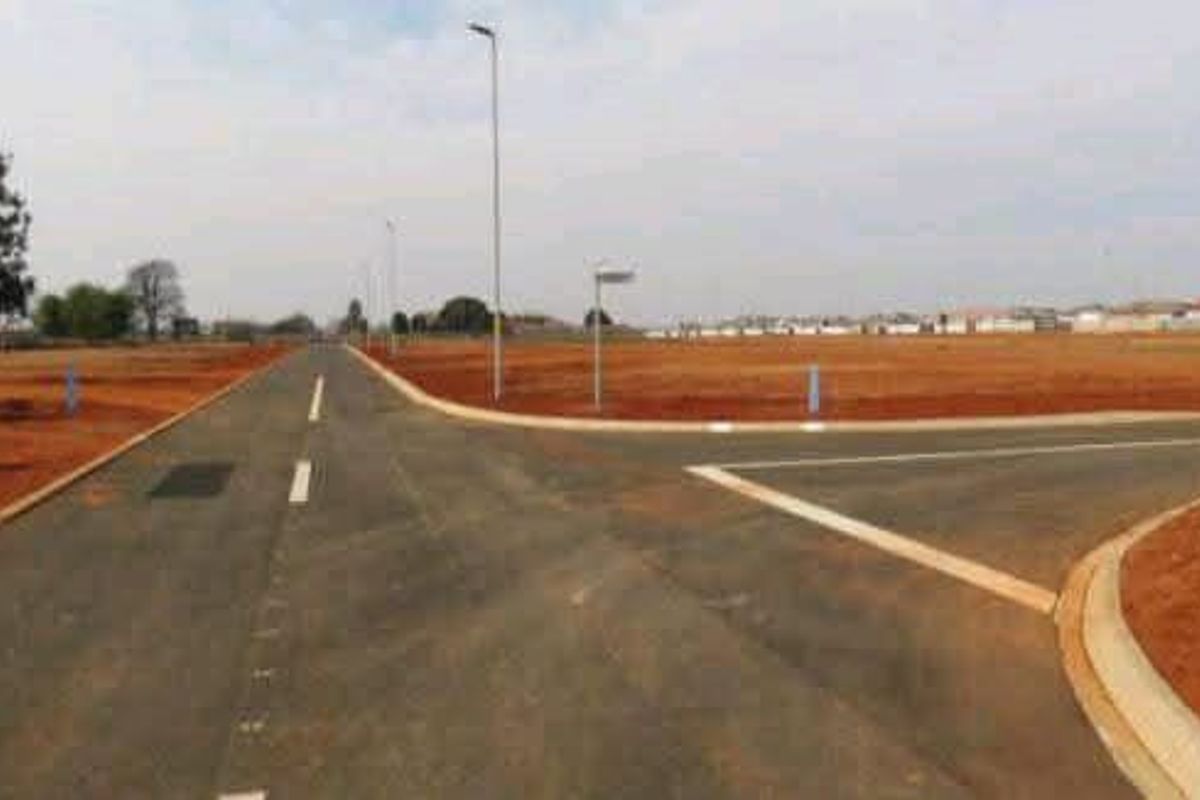 A view of a newly developed residential street with paved roads, kerbing, and installed street lighting in a vacant land development.