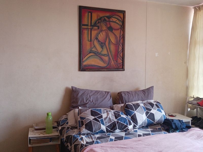 A bedroom featuring neutral wall finishes and natural light through window treatments, requiring minor cosmetic updates to improve overall condition.