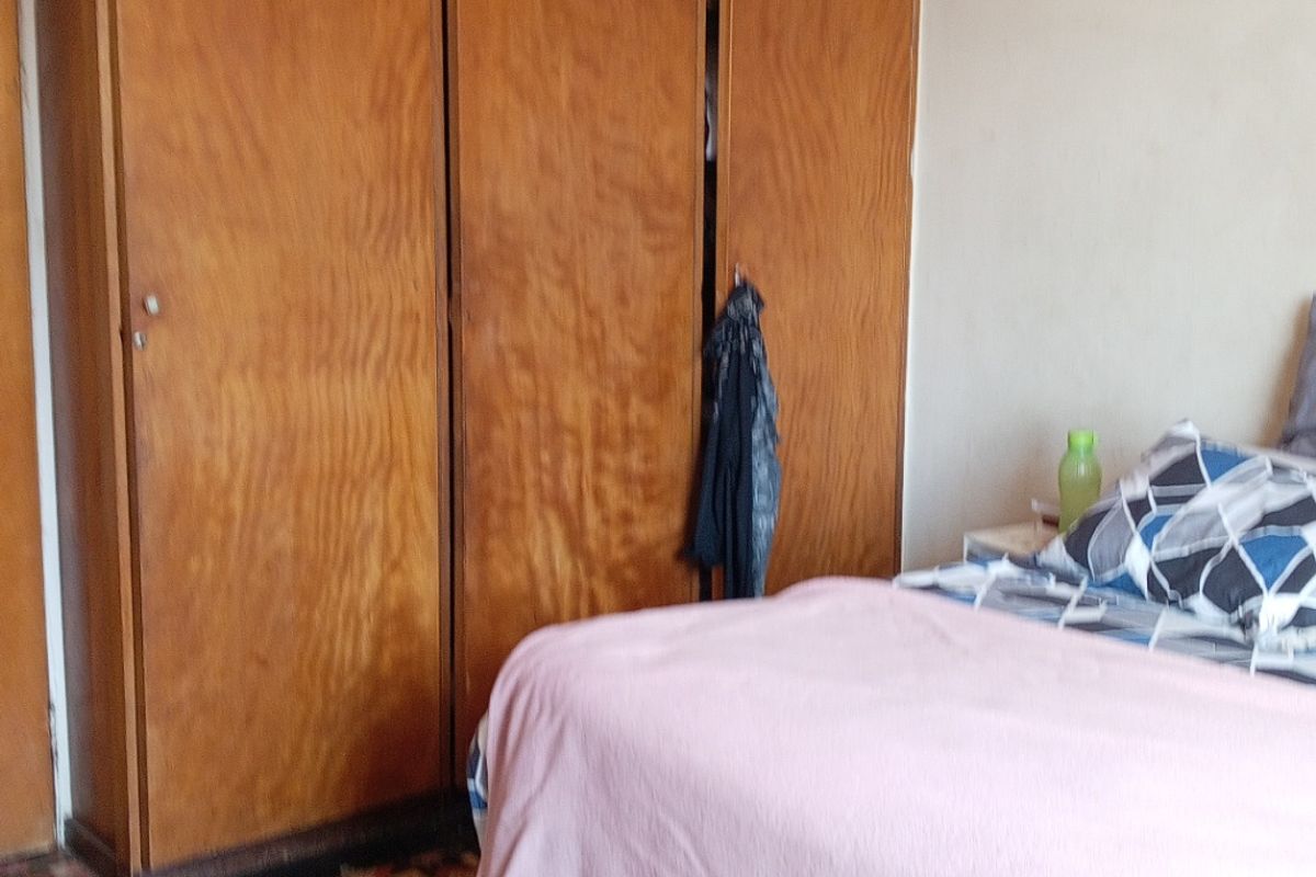 Bedroom featuring a large built-in wooden wardrobe and patterned flooring, offering potential for modernization and aesthetic updates.