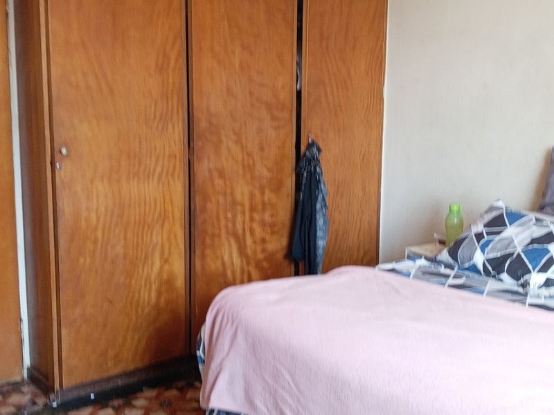 Bedroom featuring a large built-in wooden wardrobe and patterned flooring, offering potential for modernization and aesthetic updates.