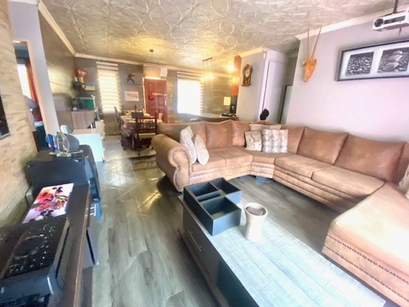 Open-plan living and dining area featuring textured ceilings, laminate flooring, and neutral wall tones, providing a versatile space for relaxation and entertaining.