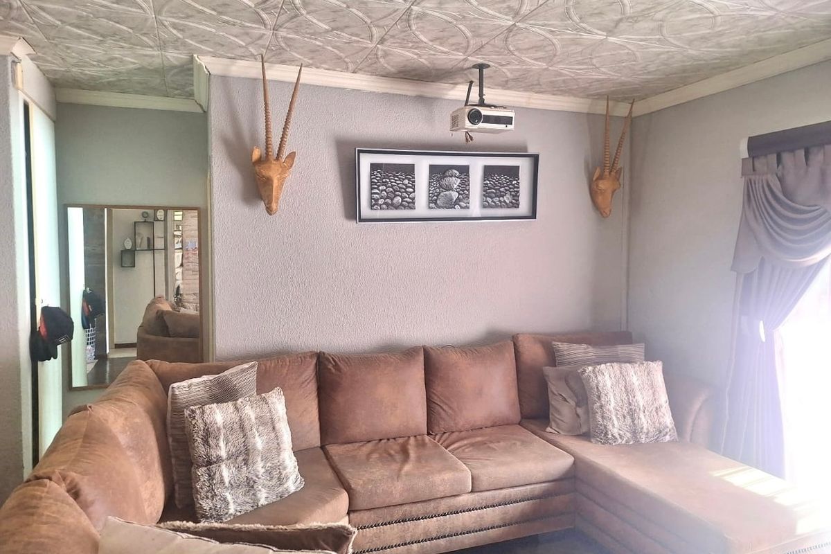 Living room featuring a textured ceiling, crown molding, and a ceiling-mounted projector, providing a functional space for entertainment.