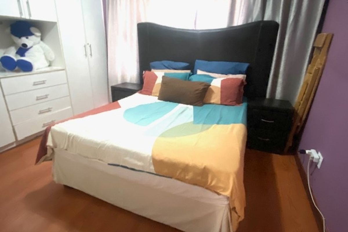 A bedroom featuring built-in wardrobes and laminate flooring, providing a functional space with integrated storage solutions.