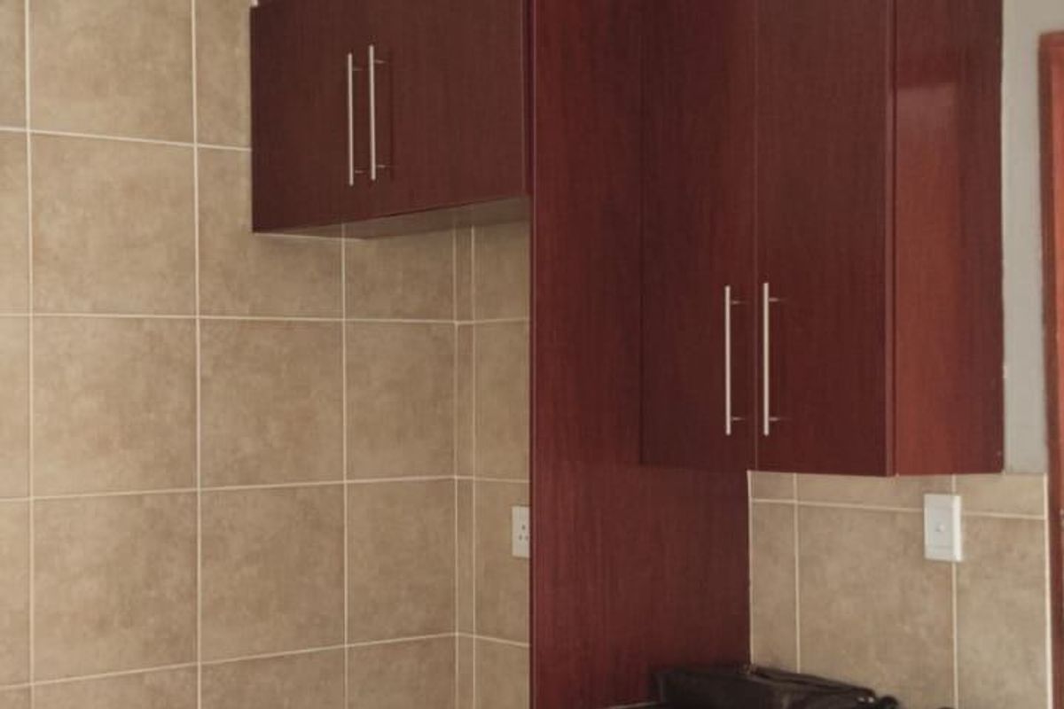 A functional kitchen corner featuring dark wood cabinetry, granite countertops, and neutral tiled splashbacks, providing a clean and practical workspace.
