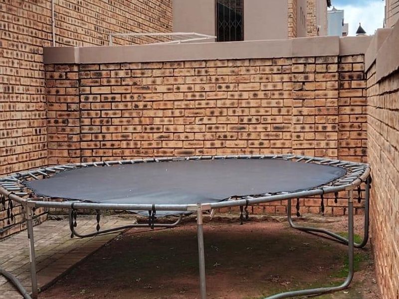 A rear courtyard area featuring face brick walls and paved sections, currently used as an outdoor play space.