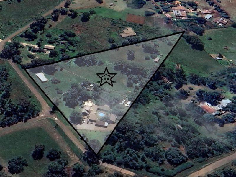 Aerial view of a large rural property featuring a main residence, swimming pool, and surrounding land with outbuildings.