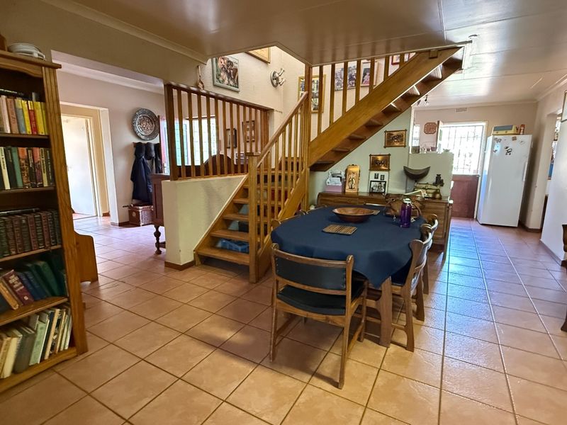 Open plan living area featuring ceramic floor tiles and a central wooden staircase with balustrade, providing access to the upper level.
