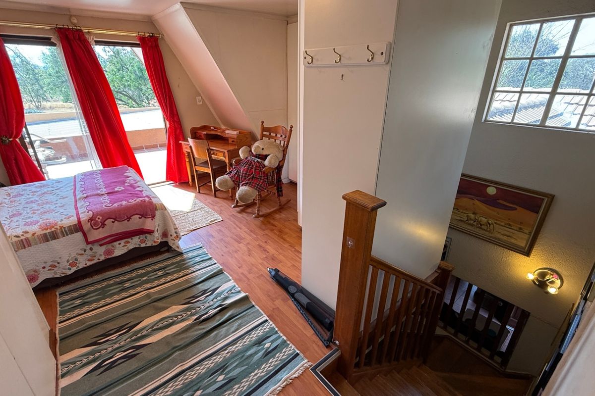 Bedroom featuring laminate flooring, sloped ceilings, and a sliding glass door leading to an outdoor area, with an adjacent staircase.