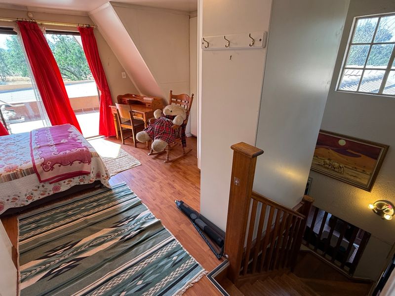 Bedroom featuring laminate flooring, sloped ceilings, and a sliding glass door leading to an outdoor area, with an adjacent staircase.