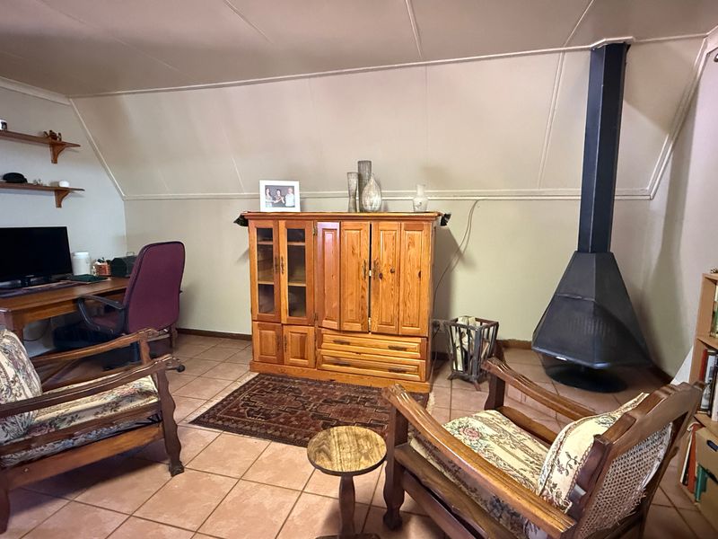 A living room featuring a freestanding fireplace, tiled flooring, and a sloped ceiling, providing a cozy and functional space.