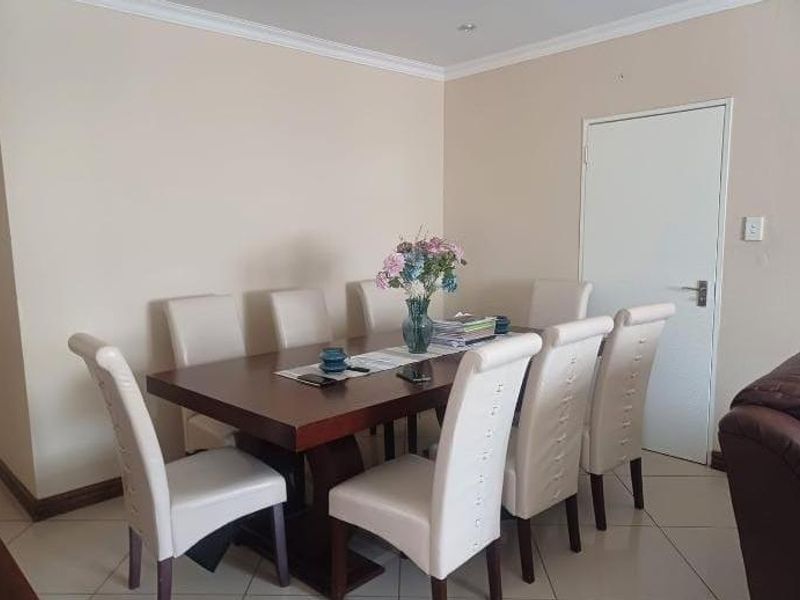 A functional dining room featuring neutral wall tones, tiled flooring, and decorative cove cornicing, providing a clean and versatile space for family meals.