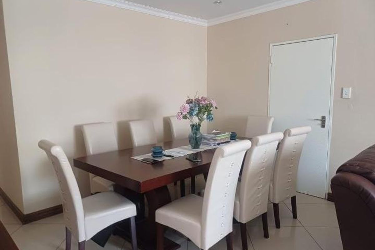 A functional dining room featuring neutral wall tones, tiled flooring, and decorative cove cornicing, providing a clean and versatile space for family meals.