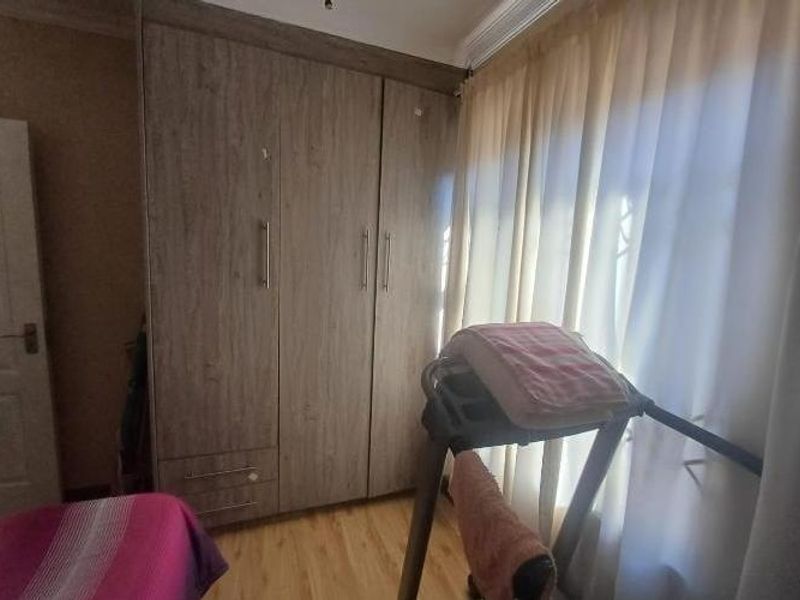 A bedroom featuring wood-look built-in cupboards and laminate flooring, providing functional storage and a neutral foundation.