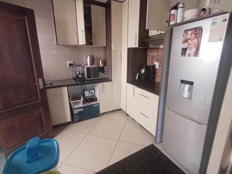 Compact kitchen featuring built-in cabinetry, granite countertops, and tiled finishes, providing a functional workspace with integrated storage solutions.