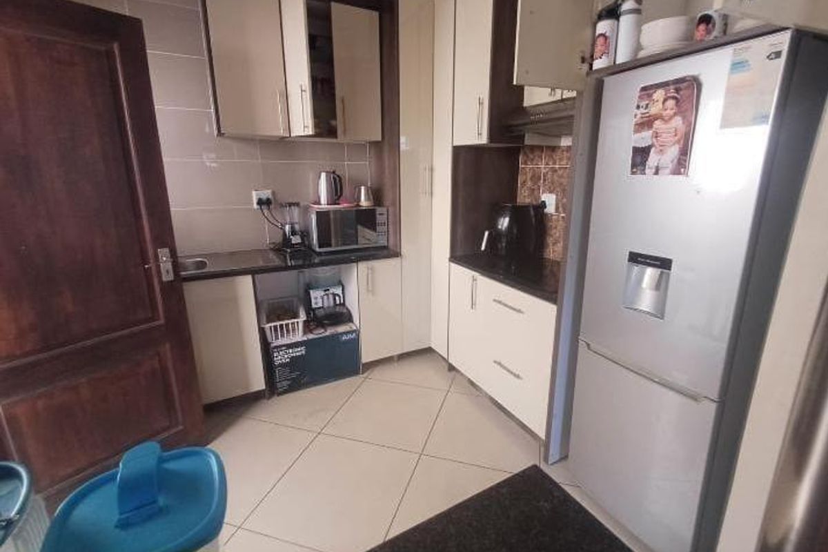 Compact kitchen featuring built-in cabinetry, granite countertops, and tiled finishes, providing a functional workspace with integrated storage solutions.