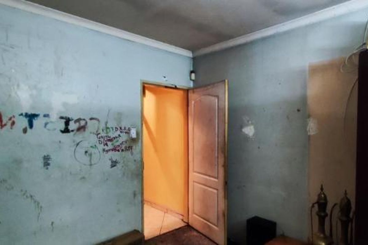 A bedroom interior requiring significant cosmetic renovation, including wall repairs and repainting to address surface damage and graffiti.