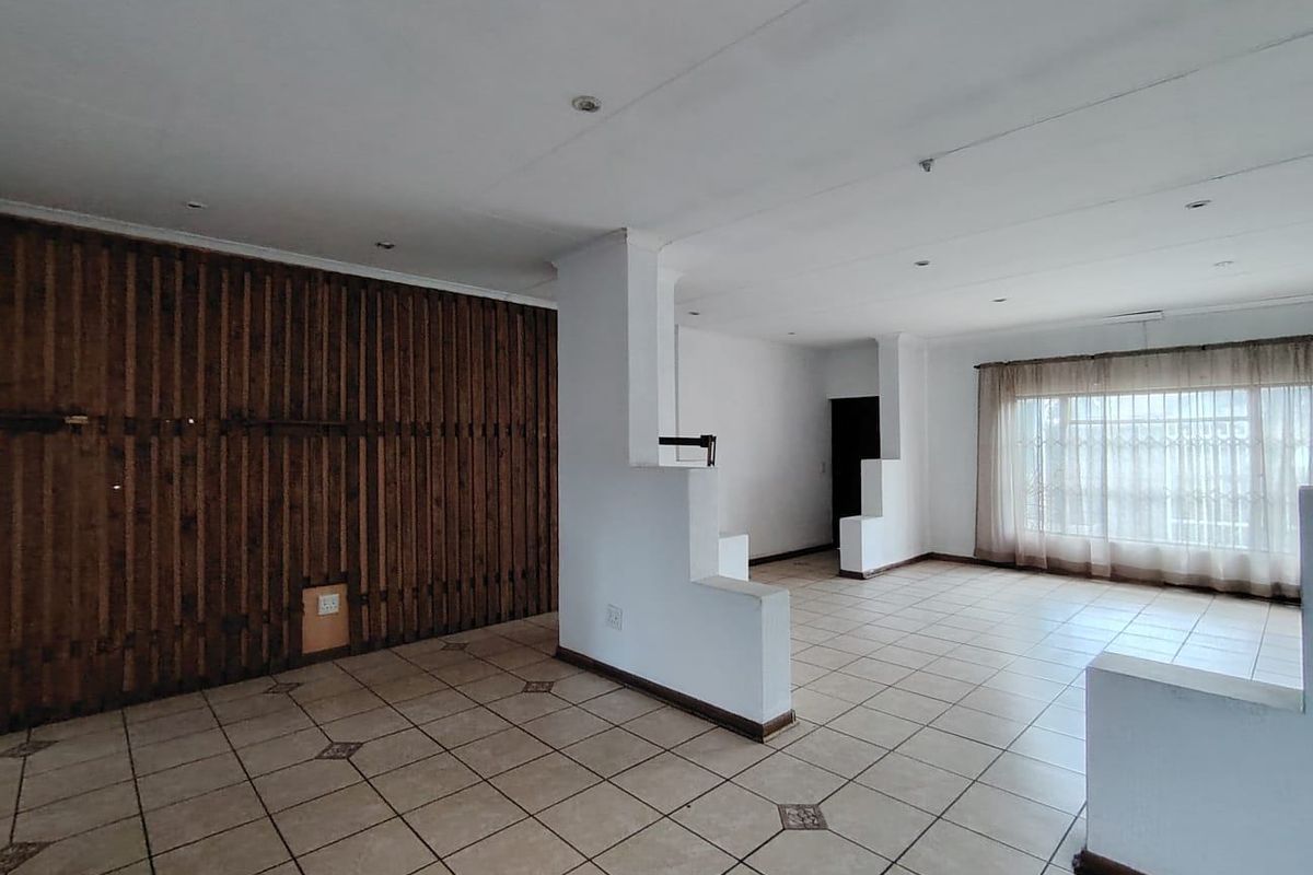 Spacious open-plan living area featuring tiled flooring, recessed lighting, and a distinctive timber-paneled feature wall.