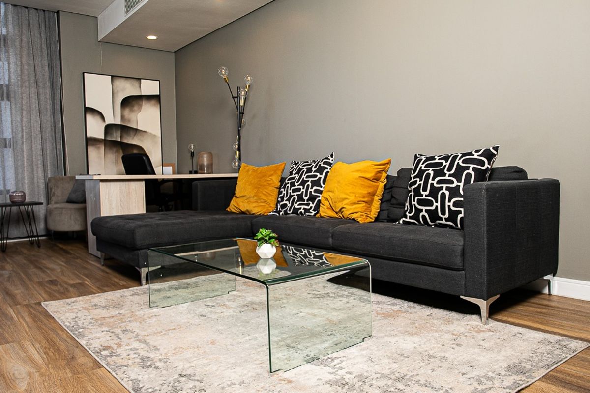 A modern, well-maintained living room featuring laminate wood flooring, recessed ceiling lighting, and integrated ducted air conditioning.