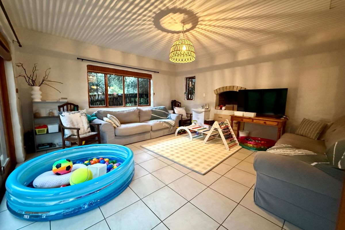 A spacious living room featuring tiled flooring, a brick fireplace, and a distinctive corrugated ceiling, offering a comfortable and functional family living space.