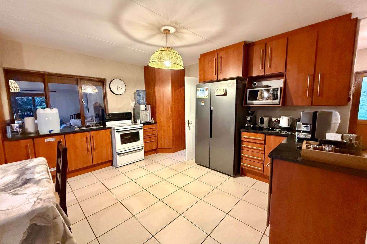A functional kitchen featuring warm-toned wooden cabinetry, dark stone countertops, tiled flooring, and a built-in microwave, offering a practical layout for daily use.