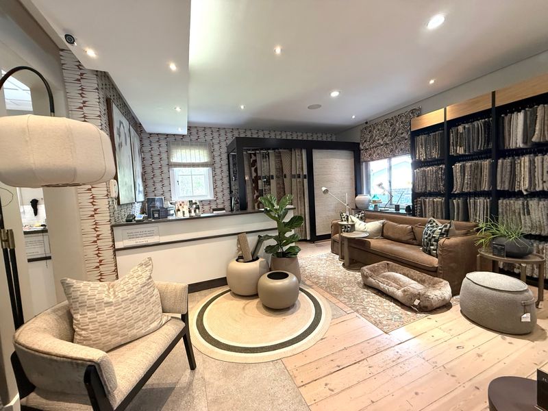A well-appointed interior space featuring timber flooring, recessed lighting, and built-in display shelving, currently utilized as a professional showroom or reception area.