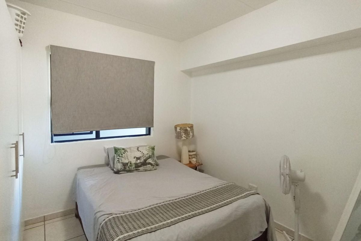 A functional bedroom featuring tiled flooring, a built-in wardrobe, and a roller blind for privacy.
