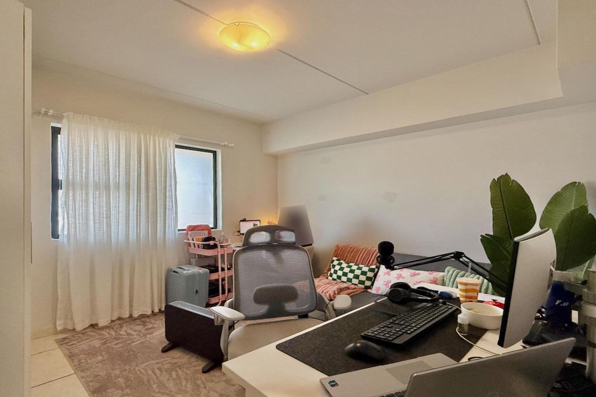 A functional bedroom featuring a built-in wardrobe and natural light through a window, providing a versatile space for rest or work.